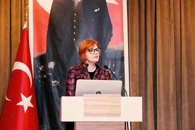 Türk bayrağı ve Atatürk posteri önünde, kürsüde konuşma yaparken