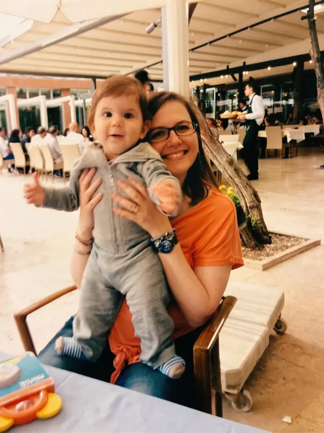Bir restoranın bahçesinde, kucağında ayakta duran bebekle